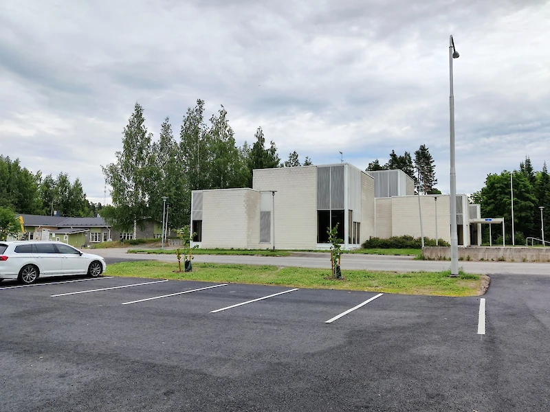 Kirjaston uusi pysäköintialue Kausansaarentien toisella puolella on jo valmistunut ja käytössä. Taustalla näkyy Peltohiiren päiväkoti, jonka sininen teemaväri on muuttunut vihreäksi.