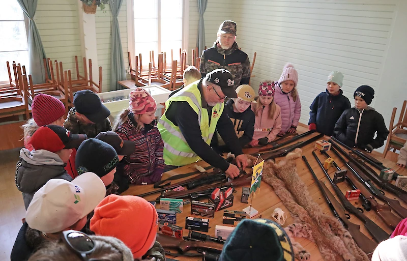 Mauri Orava (keskellä) ja Ossi Ek (takana) esittelivät lapsille metsästysaseita.